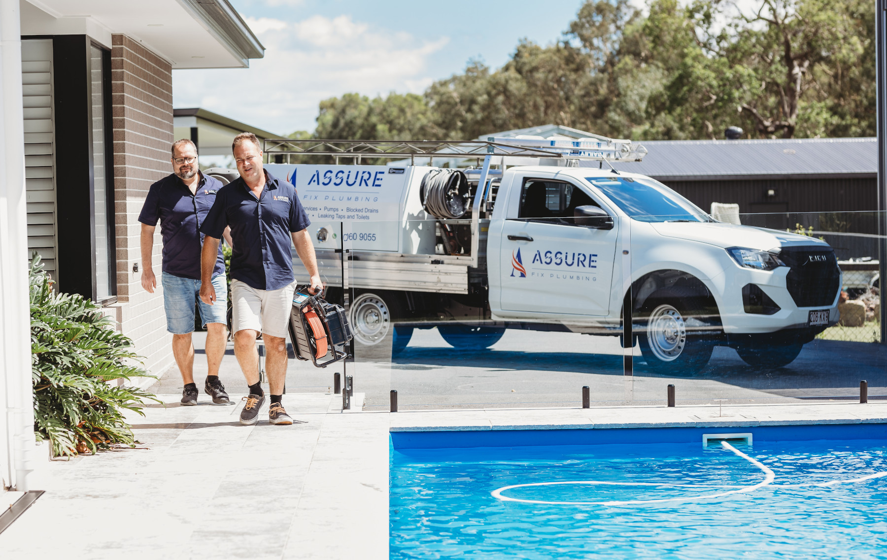 assure fix plumbers walking towards house and away from branded car