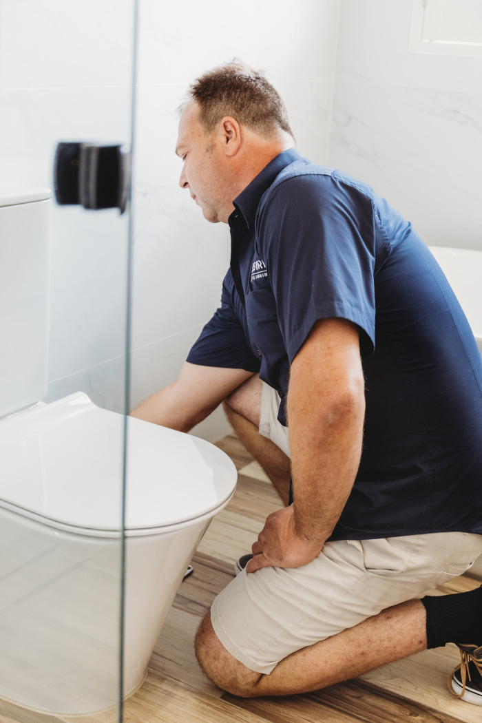 assure plumber repairing toilet