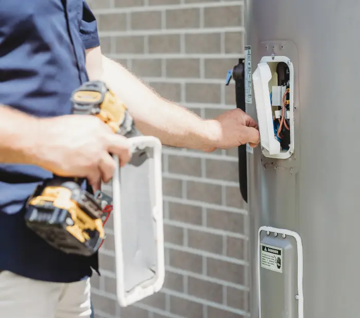 Licensed electrician repairing an exterior electrical box on a brick wall