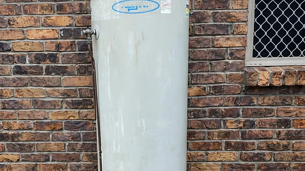Outdoor electric hot water system installed beside a brick wall at an Ipswich or Brisbane home, featured image for an electric vs solar vs heat pump hot water system comparison.